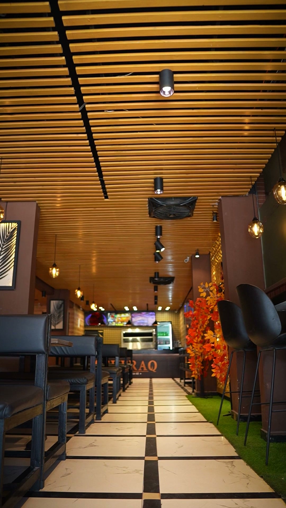 Looking down the Sufraq dining room towards the counter, booths either side of a chequered floor