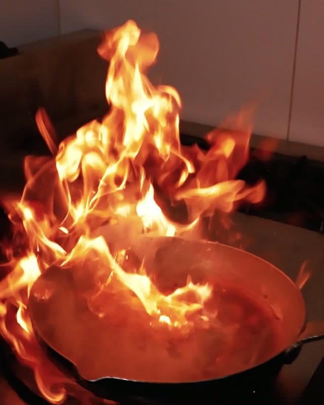A pan catching flame on the range in the Sufraq kitchen